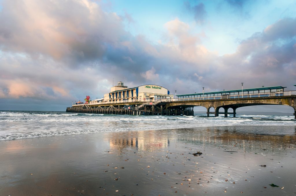 a building on the end of a pier, with the tide out