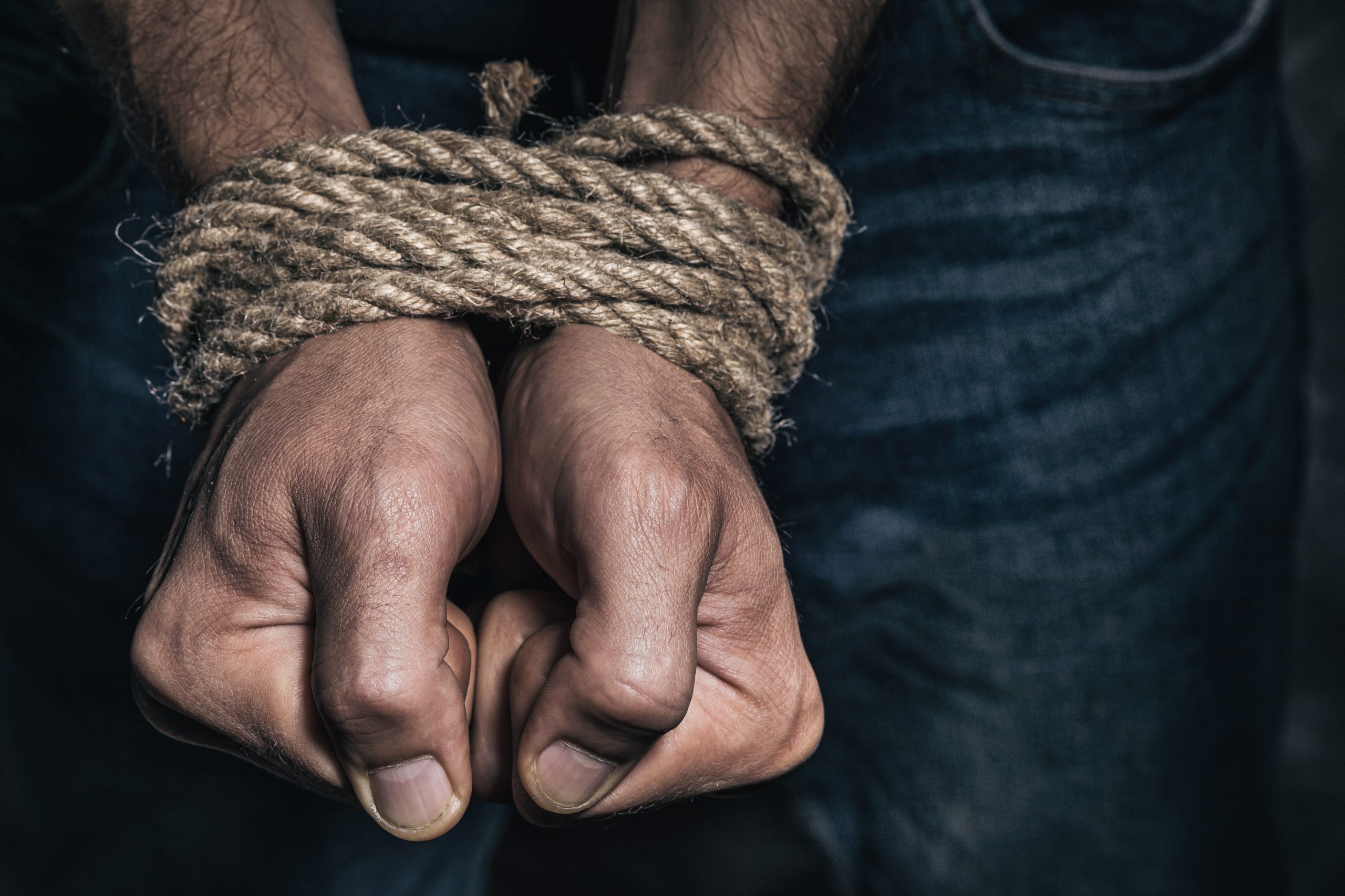 Торговля людьми и похищения. Связанные руки мужчины. Связанные руки веревкой. Мужчина с веревкой.