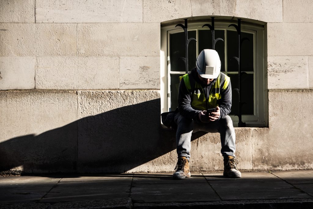 Construction worker or surveyor, sat with their head down, feeling upset and anxious