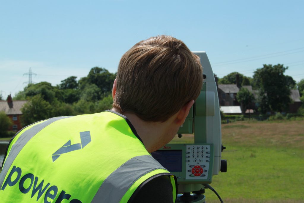 land surveyor in a field, using a total station to do a topographical survey